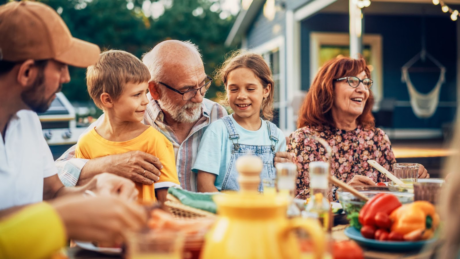 A happy senior couple enjoys a family picnic with their grandchildren and children.