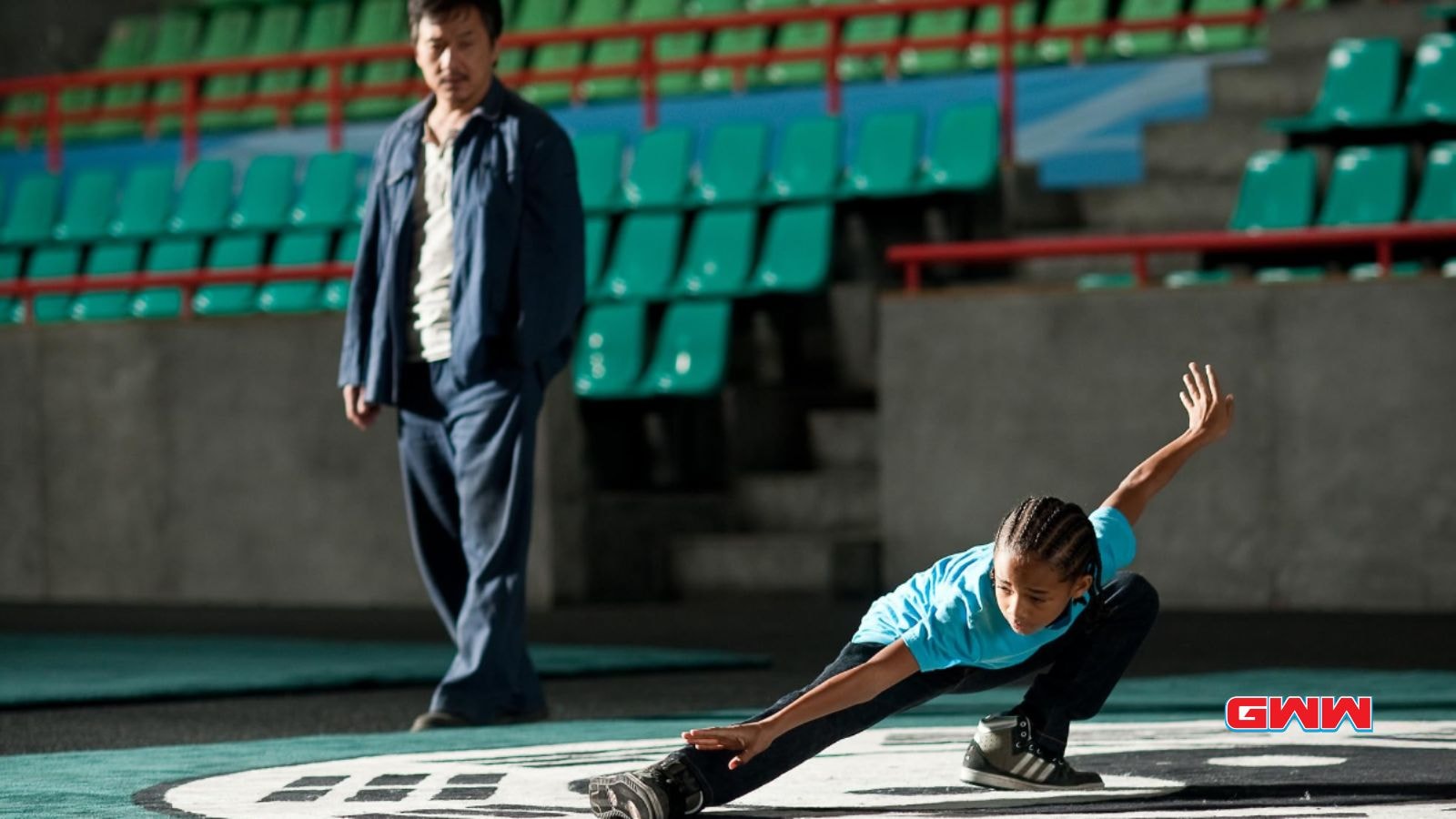 Boy practicing martial arts under Mr. Han's supervision in an empty arena.