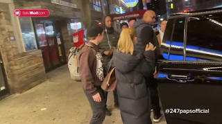 A group of people standing on a sidewalk

Description automatically generated