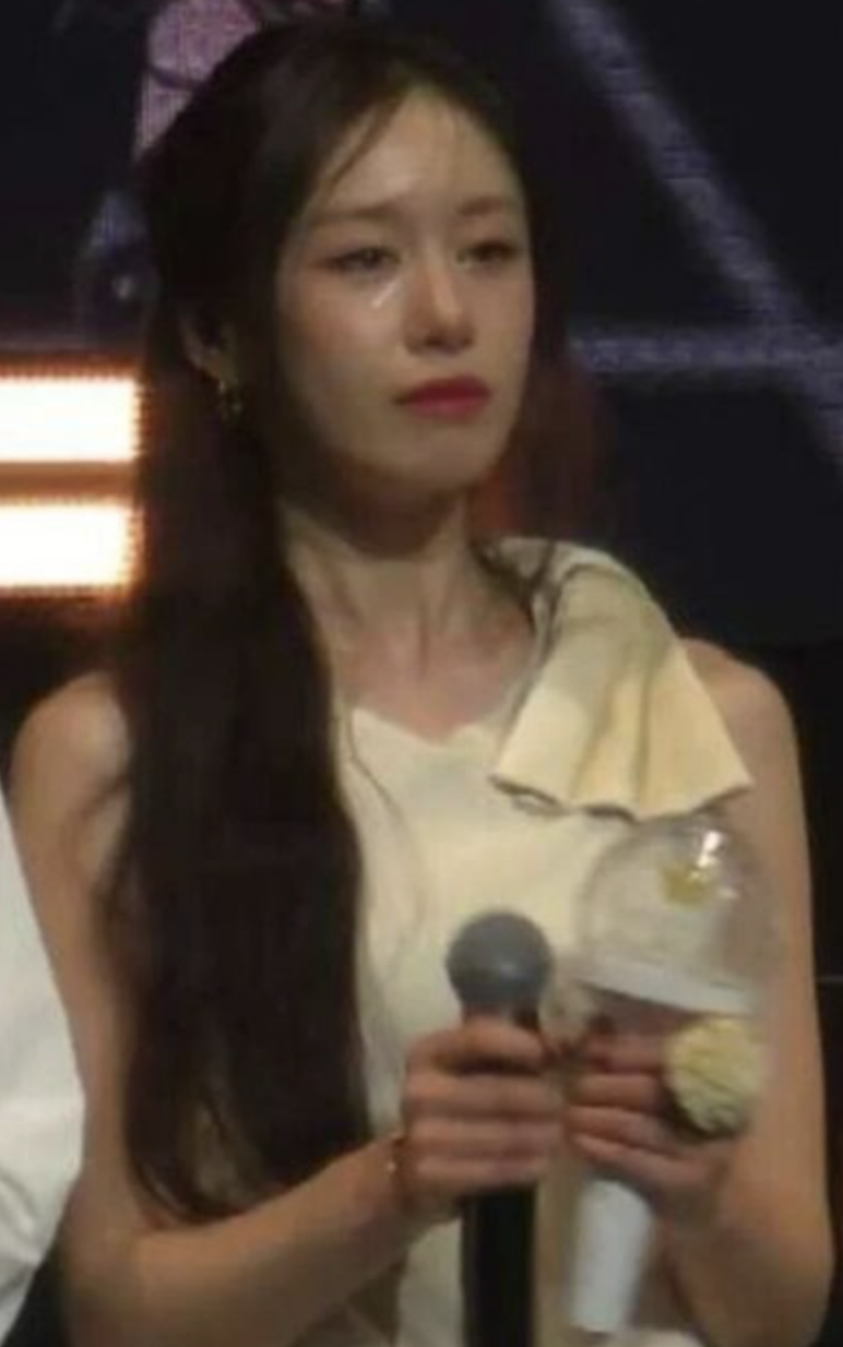  A picture of Jiyeon T-ara crying on stage with a mic on her hand 