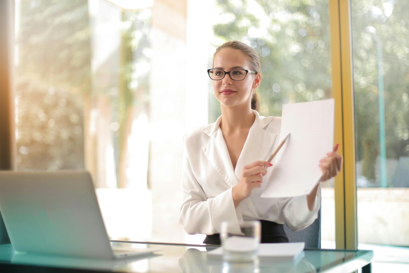 A woman holds and explains a document in an office.