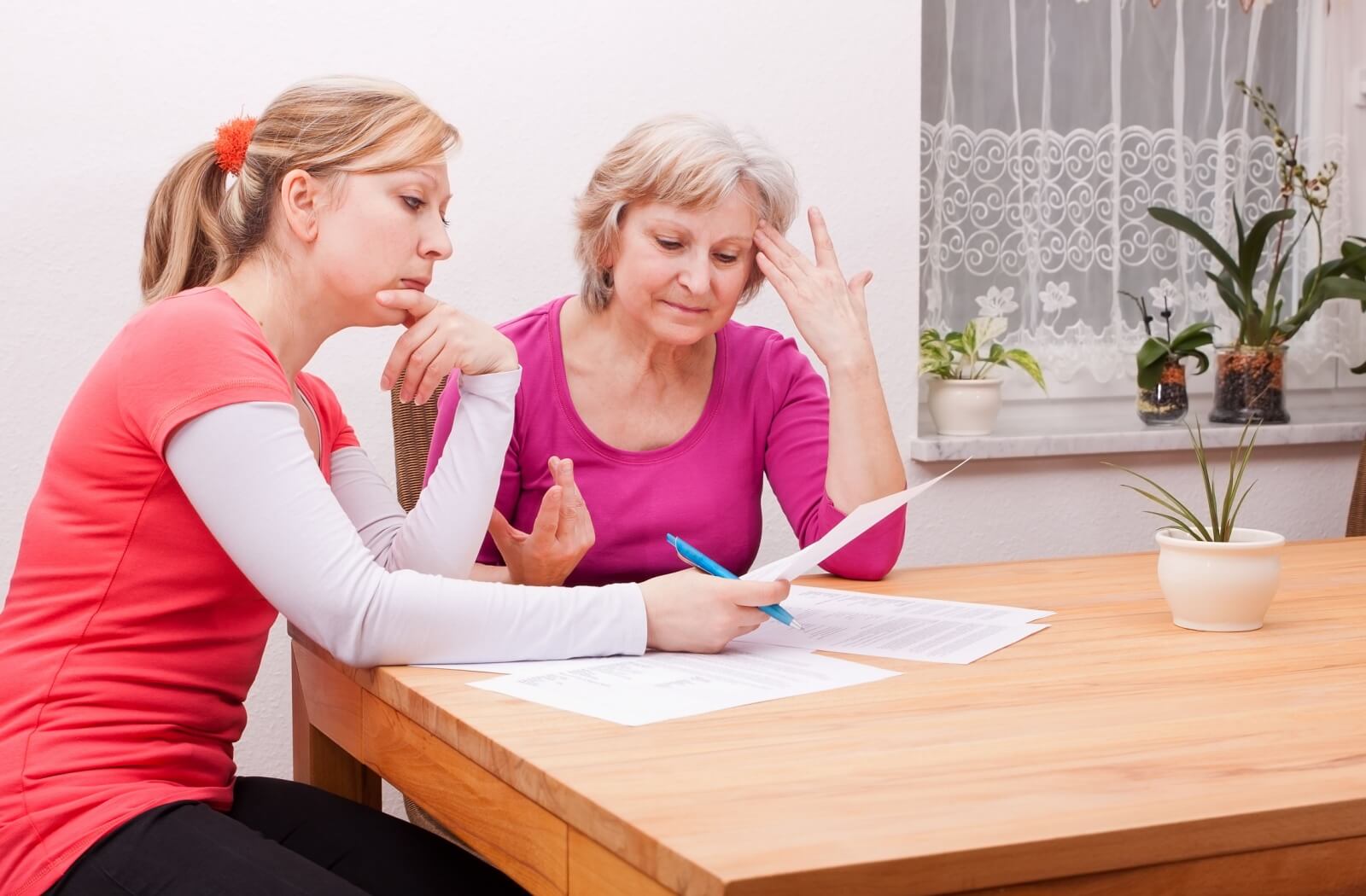 An older adult child reviewing legal documents with their elderly parent