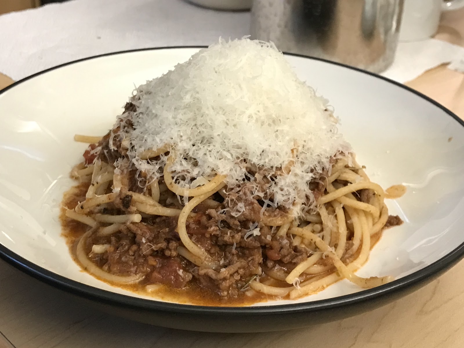 A bowl full of pasta and sauce with a topping of parmesan.