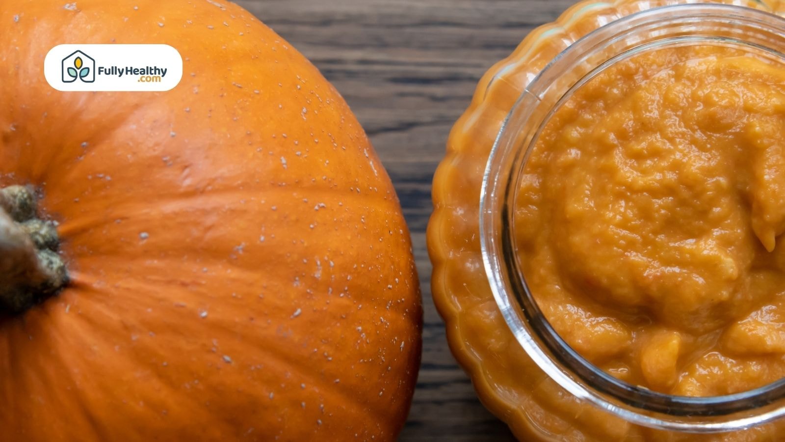 Glass jar of pumpkin puree beside whole pumpkin