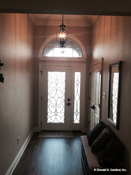 The foyer has an intricate glass front door topped with an arched transom.