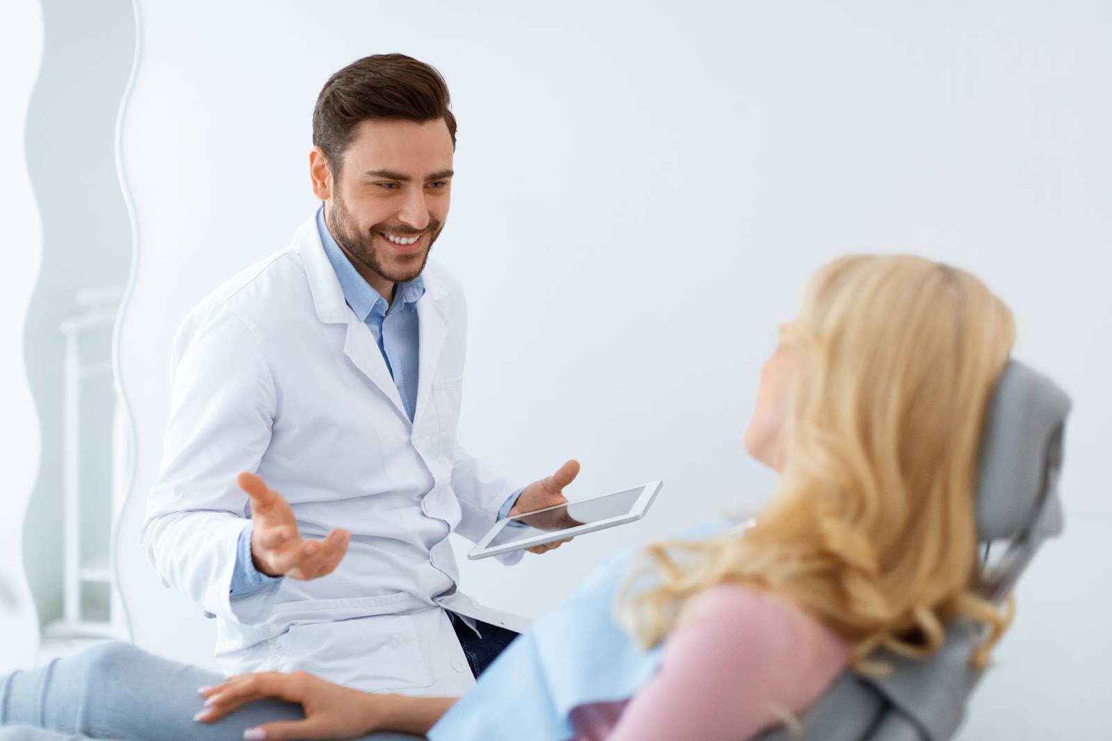 A dentist discussing findings with a patient in a chair after performing a dental exam.