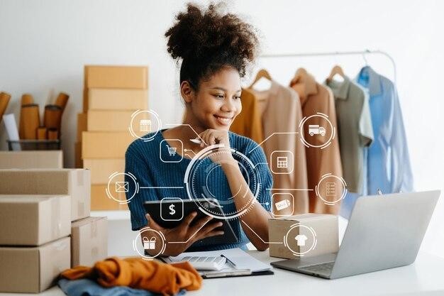 African Woman using a laptop smartphone and tablet and writing notebook at the modern office of her business online shopping In home with virtual icon, Picture