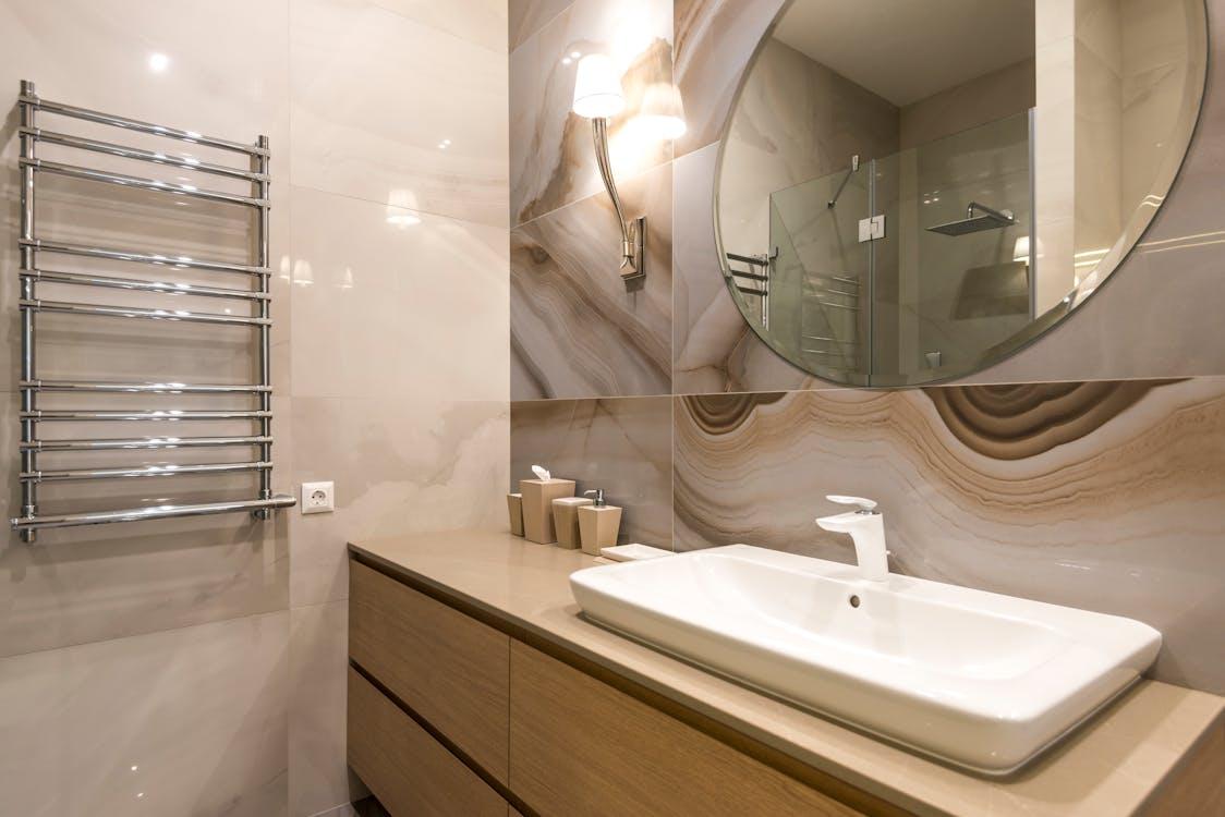 Free Elegant contemporary bathroom with marble tiles, mirror, and stylish fixtures. Stock Photo