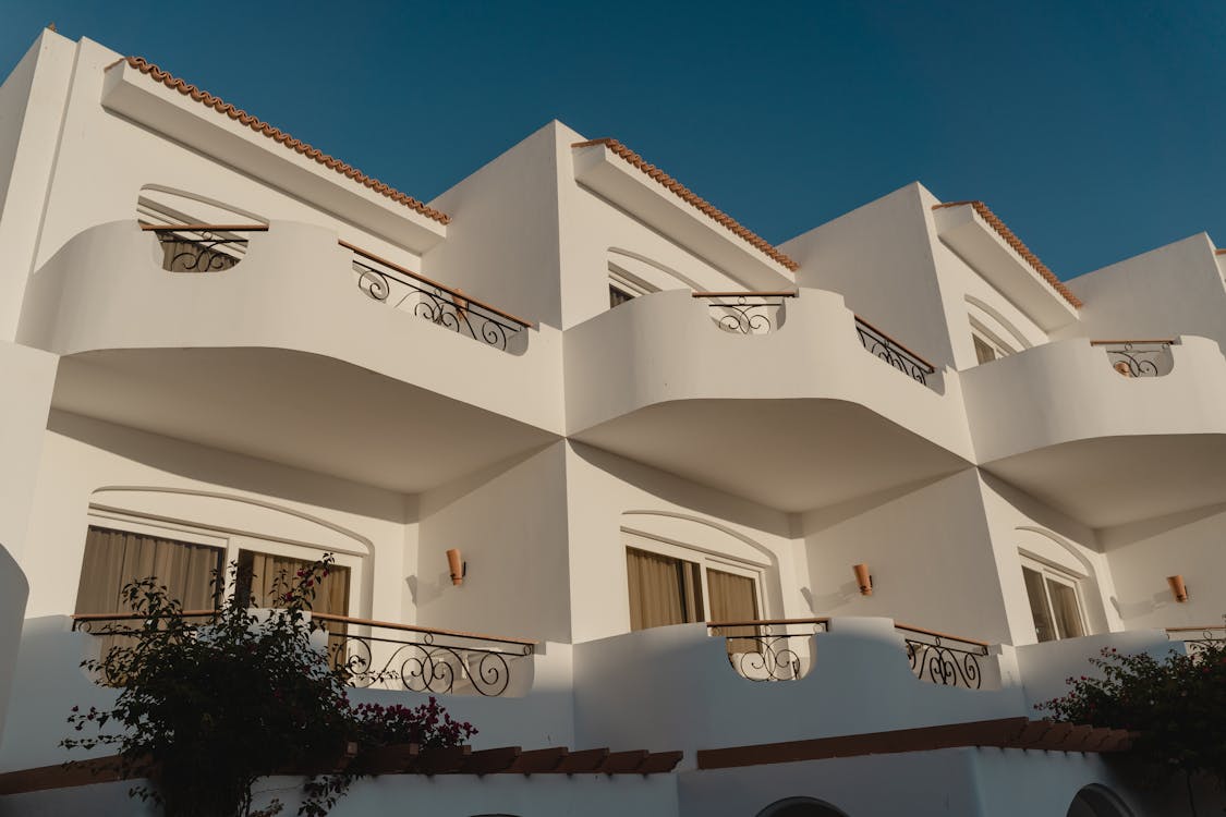 Free Elegant classic white Mediterranean building with ornate balconies under a clear blue sky. Stock Photo