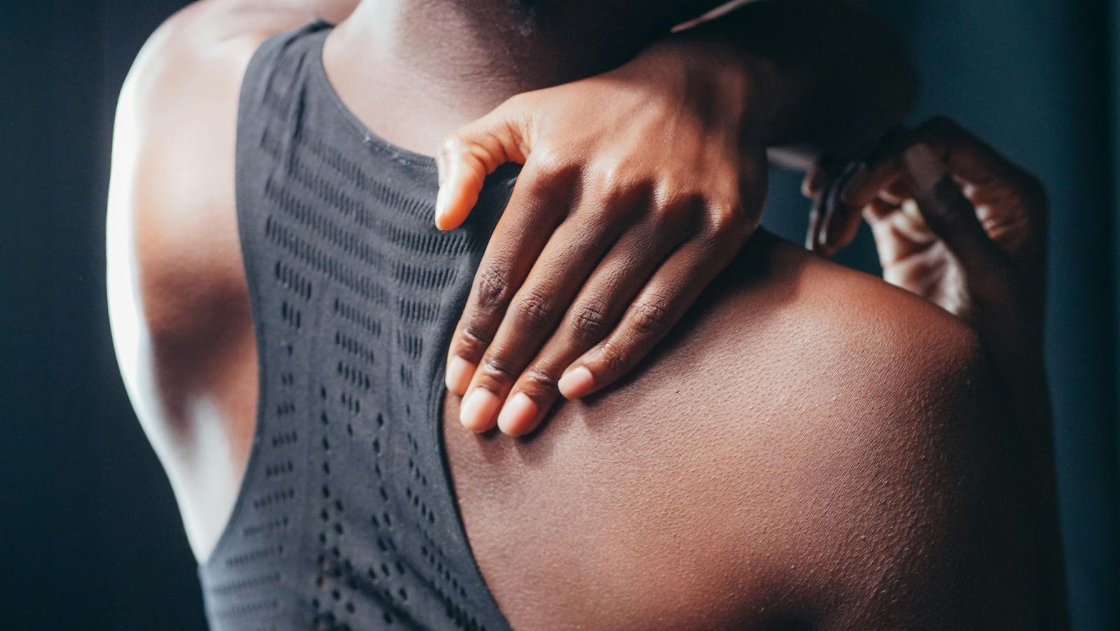 A person holds their right shoulder because of muscle pain.