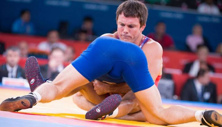 college wrestlers tackling each other in competition with wrestler in blue's ass in the air