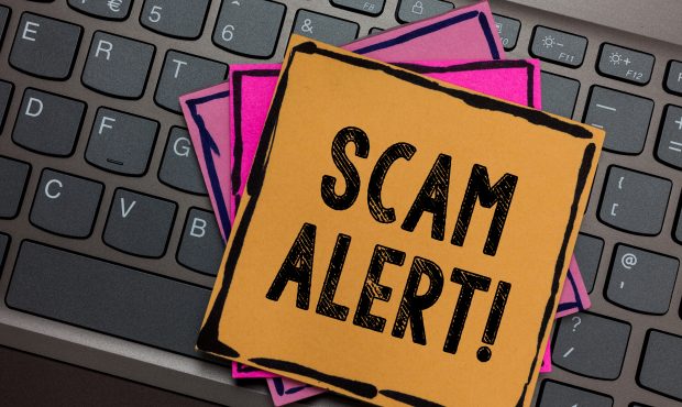 A “Scam Alert!” sign placed on a laptop keyboard