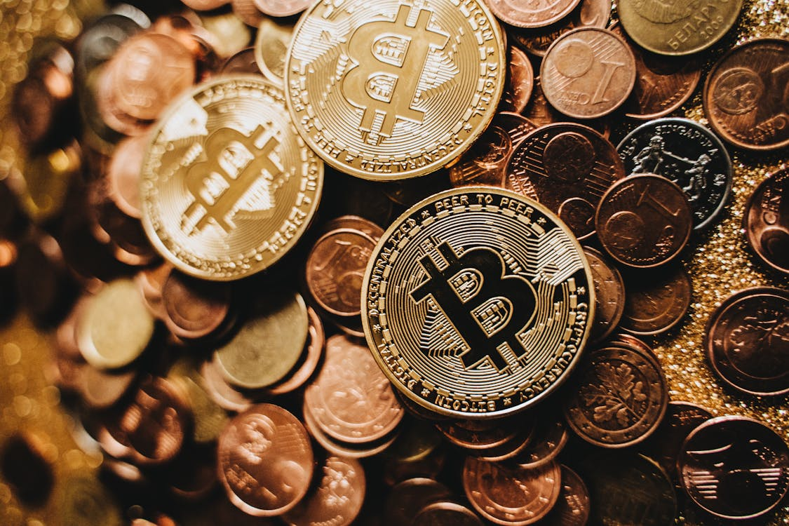 3 Bitcoin coins with a copper-colored background of smaller cent coins symbolizing cryptocurrency investment