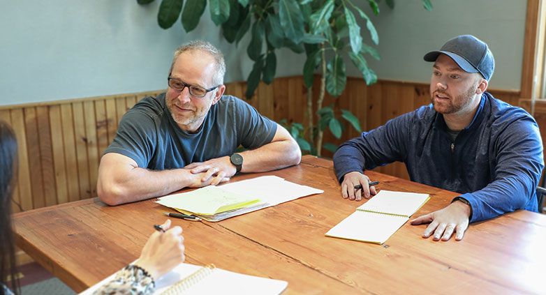 A group of people at a table, focused on a guide about helping family members with addiction.