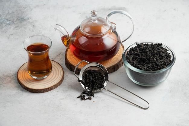 a glass teapot with tea on wooden board.