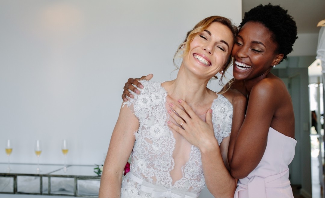 Happy bride and wedding guest embracing each other.