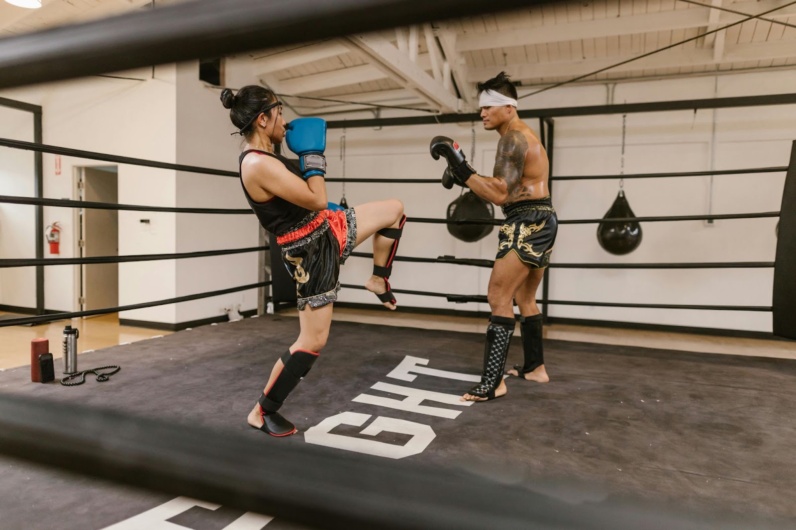 A male martial arts practitioner prepares to block a kick from a female practitioner in a training studio