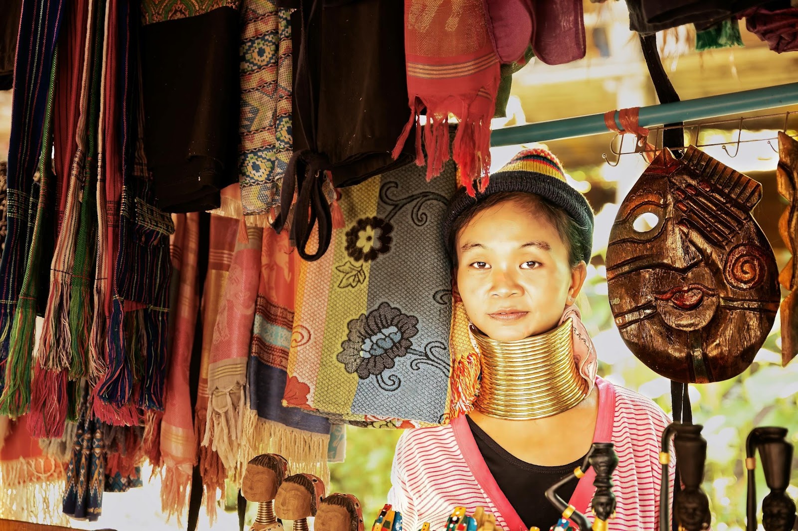 A person with large metal rings around her neck

Description automatically generated