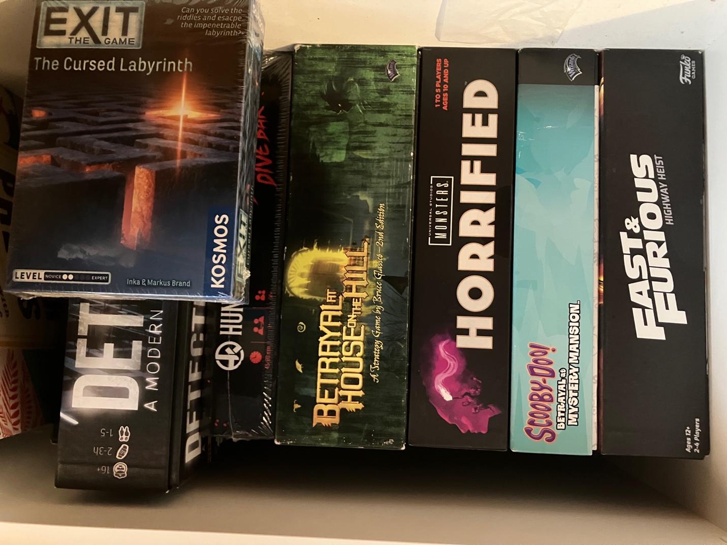 A stack of board game boxes, including Exit: The Game, Horrified, Scooby-Doo! Mystery Mansion, and Fast & Furious: Highway Heist.