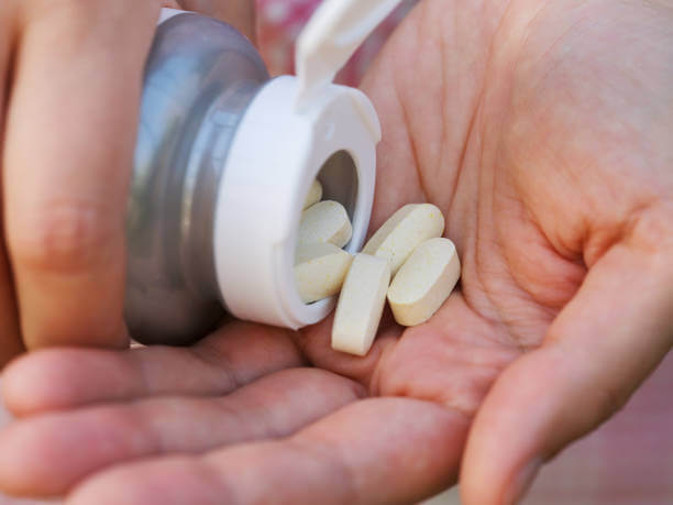 Close-up of a person holding magnesium supplements in their hand, preparing to take them.