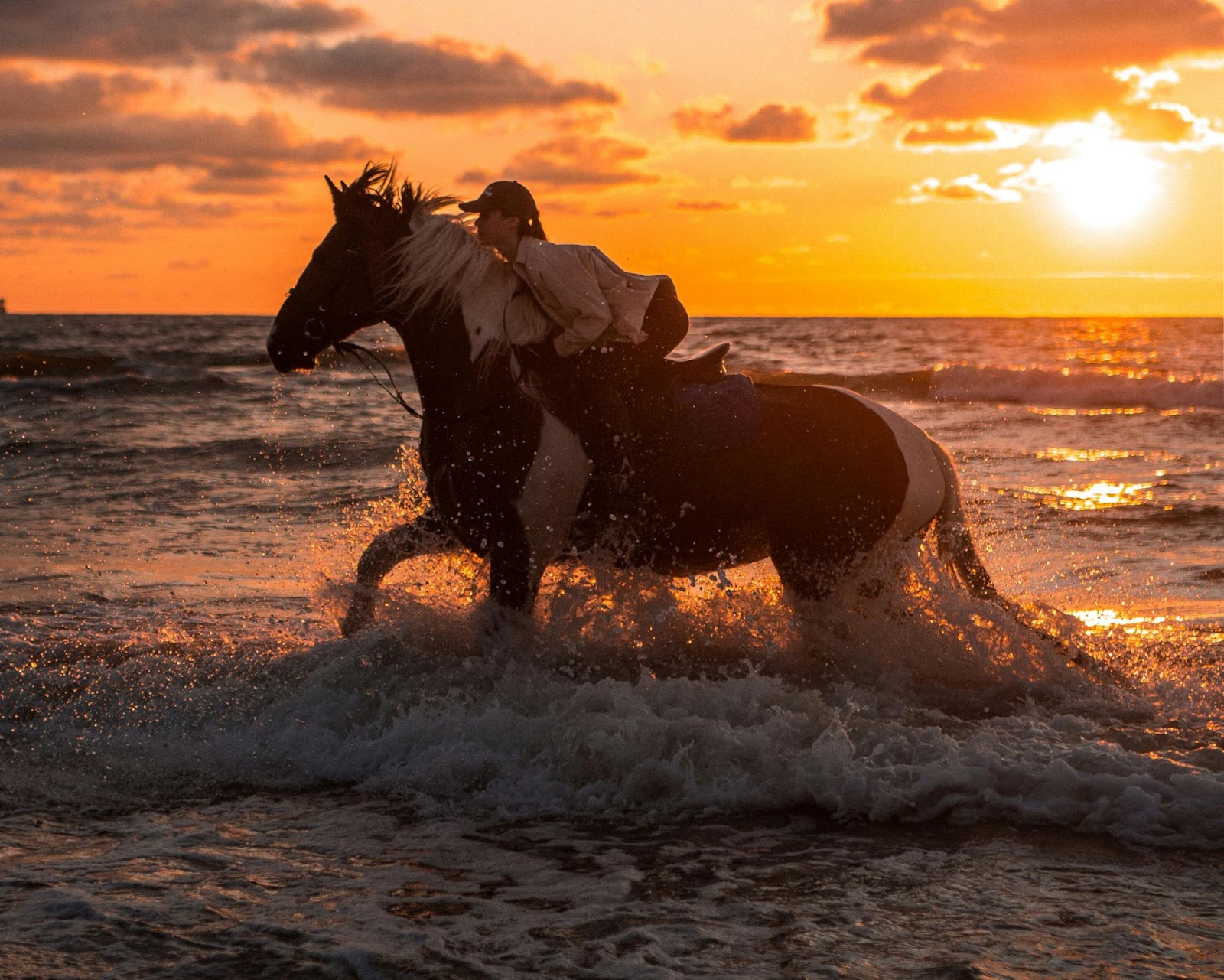 A woman riding horse on beach.