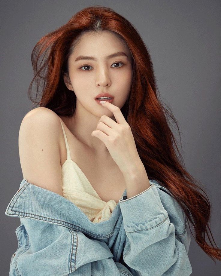 A picture of Han So Hee wearing a off-white singlet and a jean jacket with her hand on her lip 