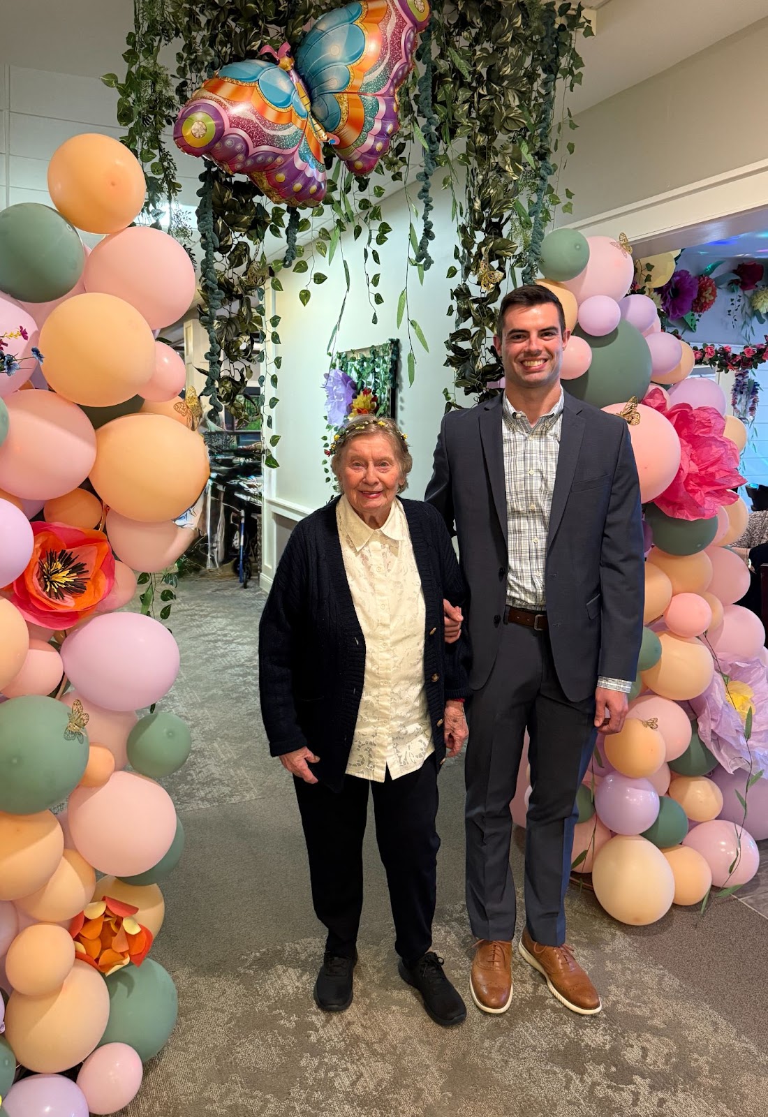 Woman and grandson smile in front of balloon arch
