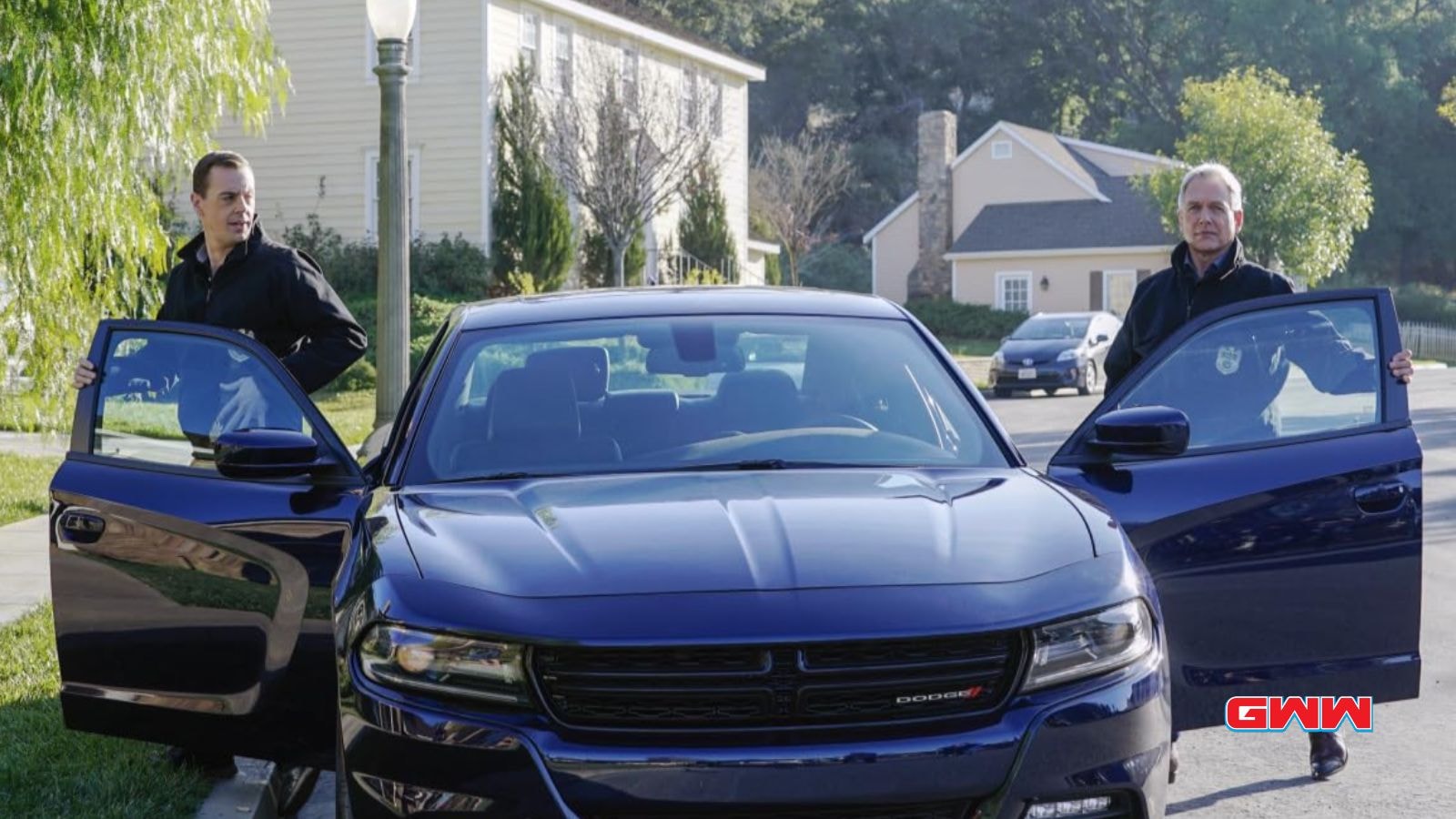 Timothy and Leroy standing beside a blue car, both holding car doors open.