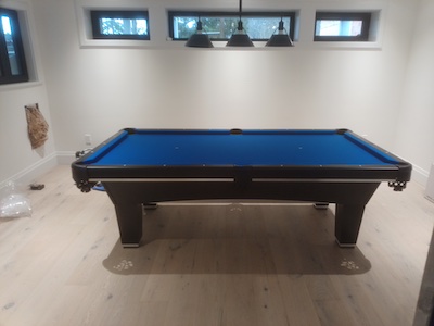 Blue felt pool table in a basement.