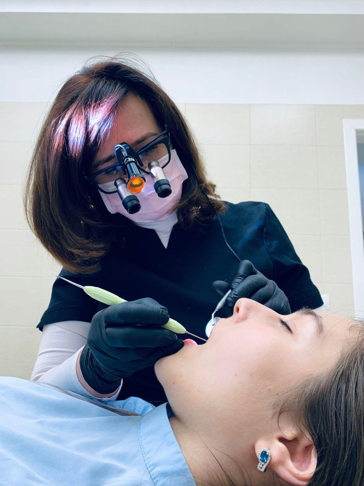 A dentist examining a woman patient preventative vs restorative dentistry