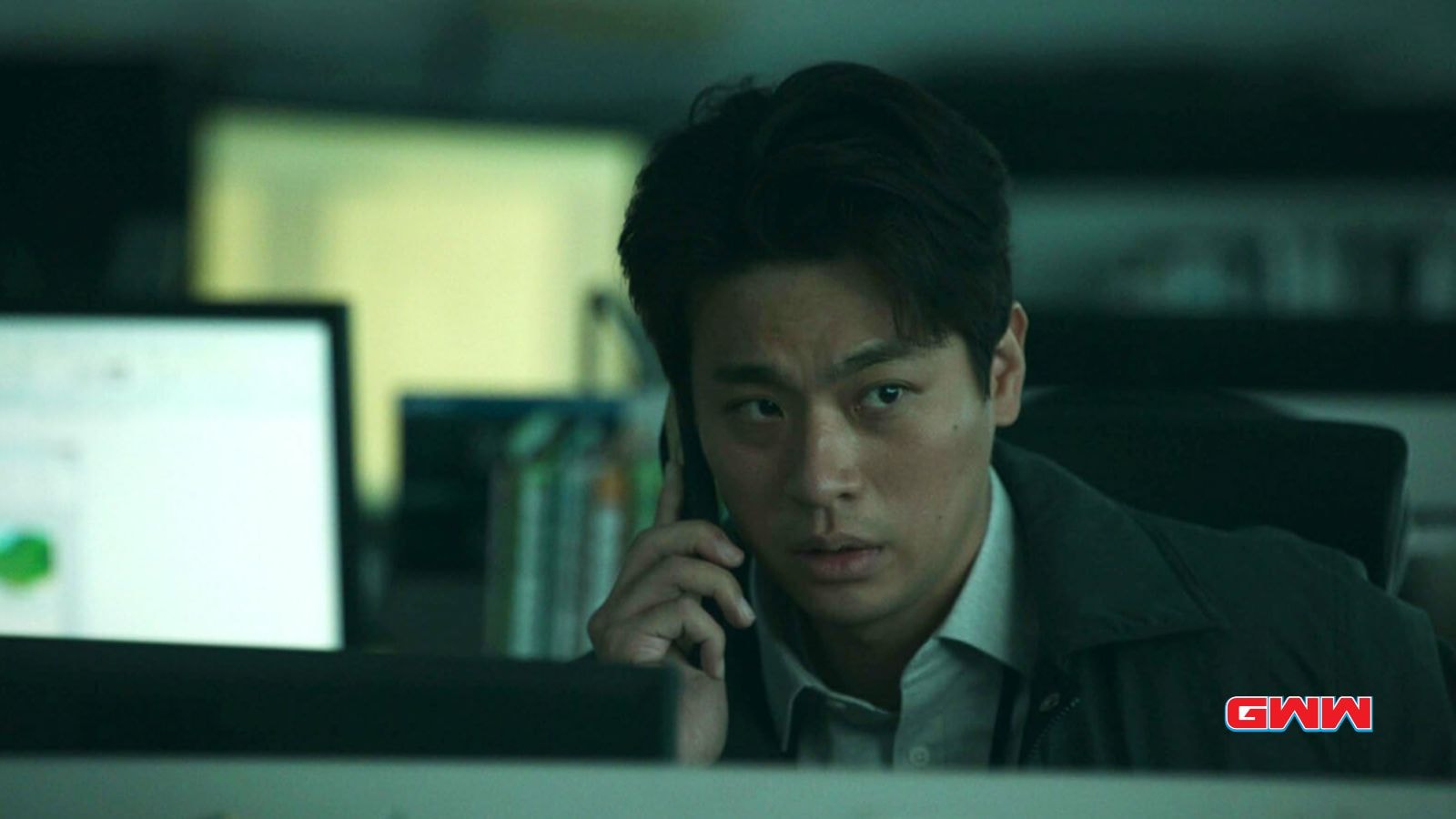 Park Jeong-min talking on a phone in a dimly lit office.