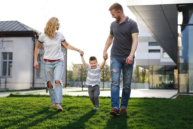 mom and dad whirl their son and have fun walking outside