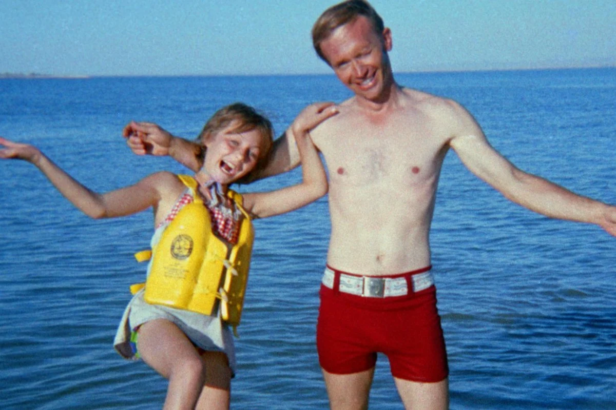 Berchtold y Jan posando en la playa. La niña lleva un salvavidas amarillo, mientras que el hombre está posando en bañador rojo.