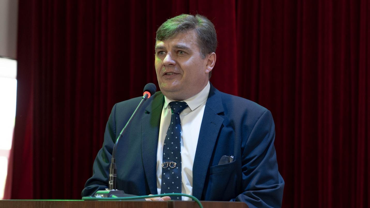 A person in a suit and tie standing at a podiumAI-generated content may be incorrect.