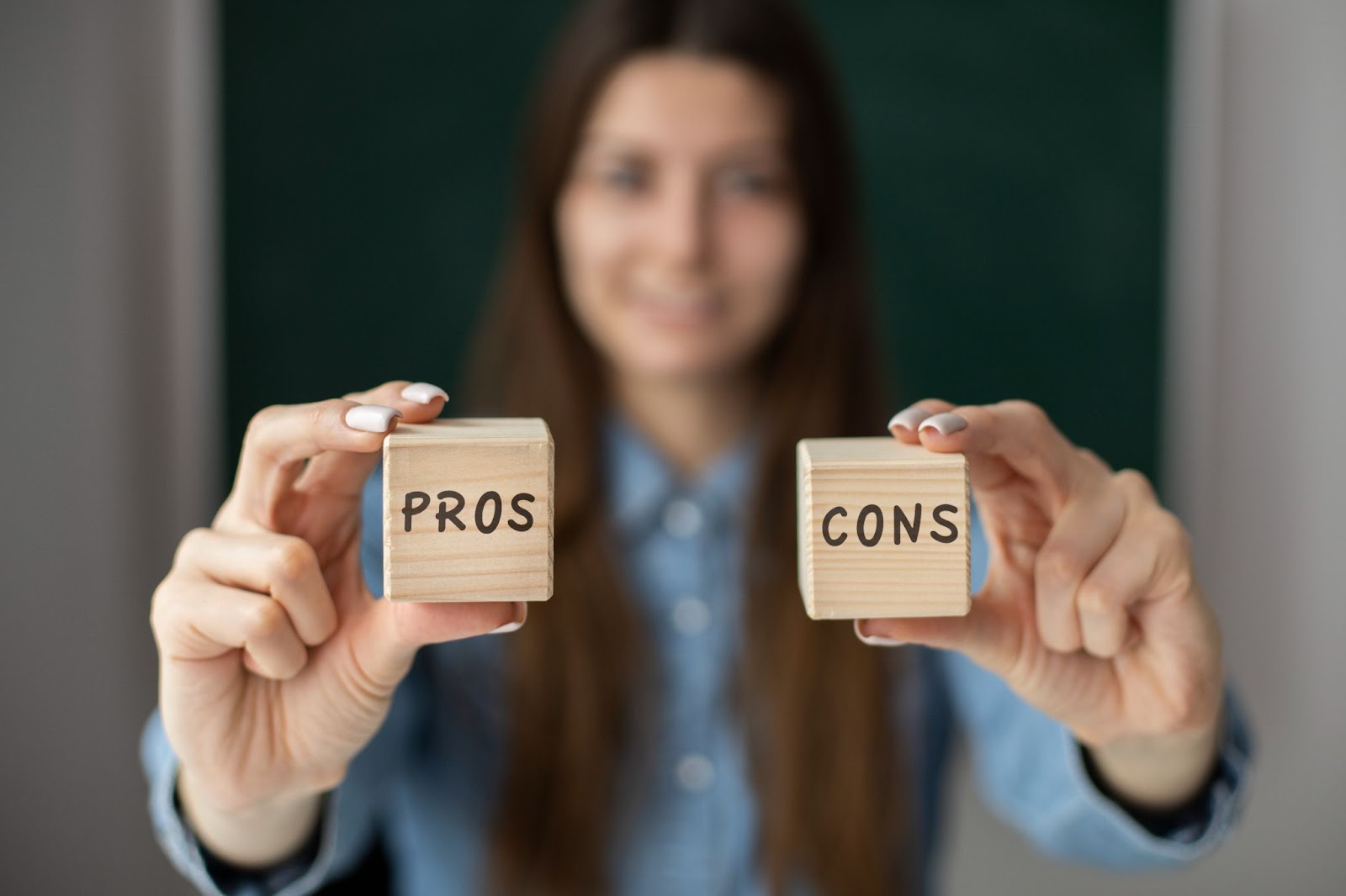 Woman holding 2 cubes with "pros and cons" written