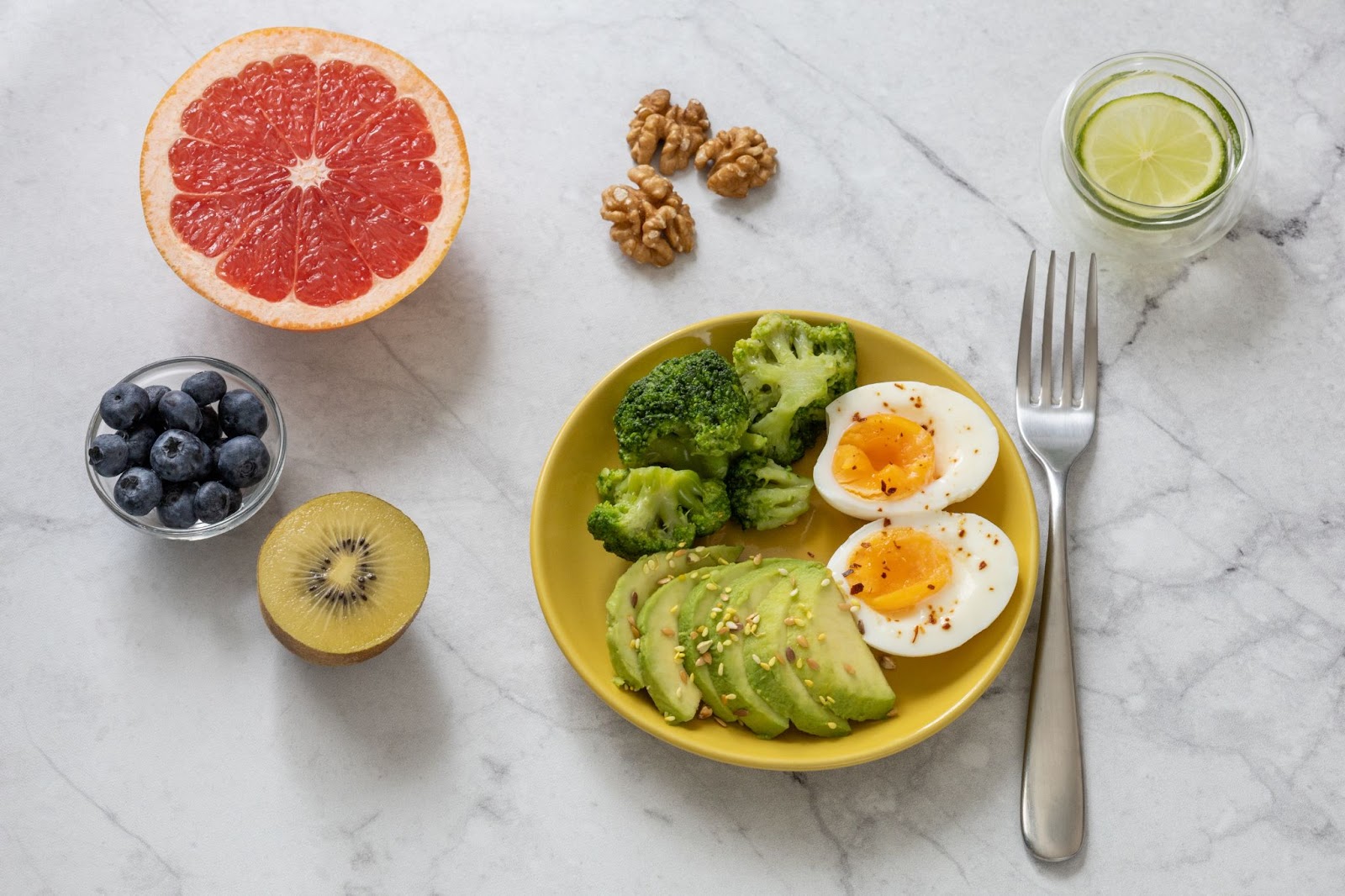 A colorful and nutritious breakfast featuring boiled eggs, avocado slices, broccoli, grapefruit, blueberries, and kiwi, highlighting foods that support your metabolism for weight loss.