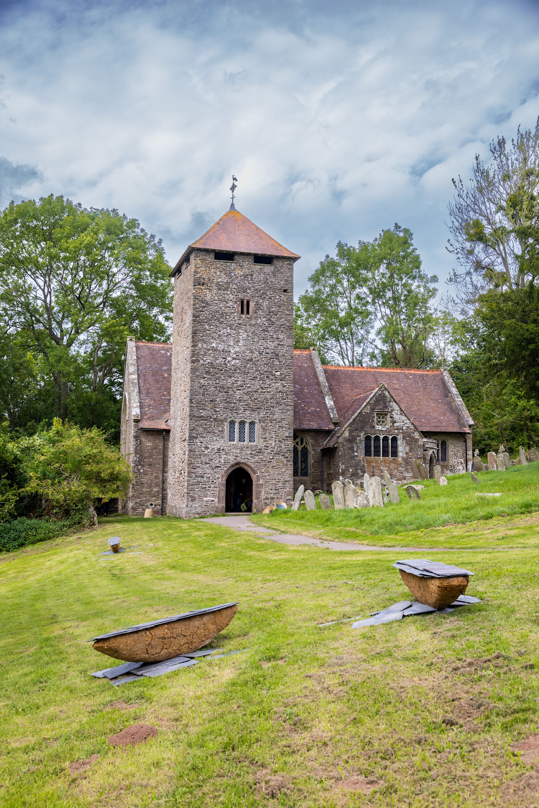 A stone building with a tower and a cemetery

Description automatically generated