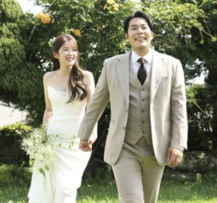 This contains an image of  Kim Hae Jun on a suit and  Kim Seung Hye on a wedding gown looking  happy