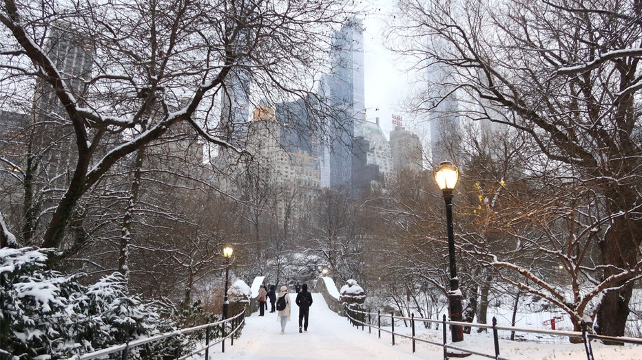 NEW YORK, NY - JANUARY 16: People walk over the Gapstow Bridge as snow falls in Central Park on January 16, 2024 in New York City. The City received a rare accumulation of snow overnight. (Photo by Gary Hershorn/Getty Images)