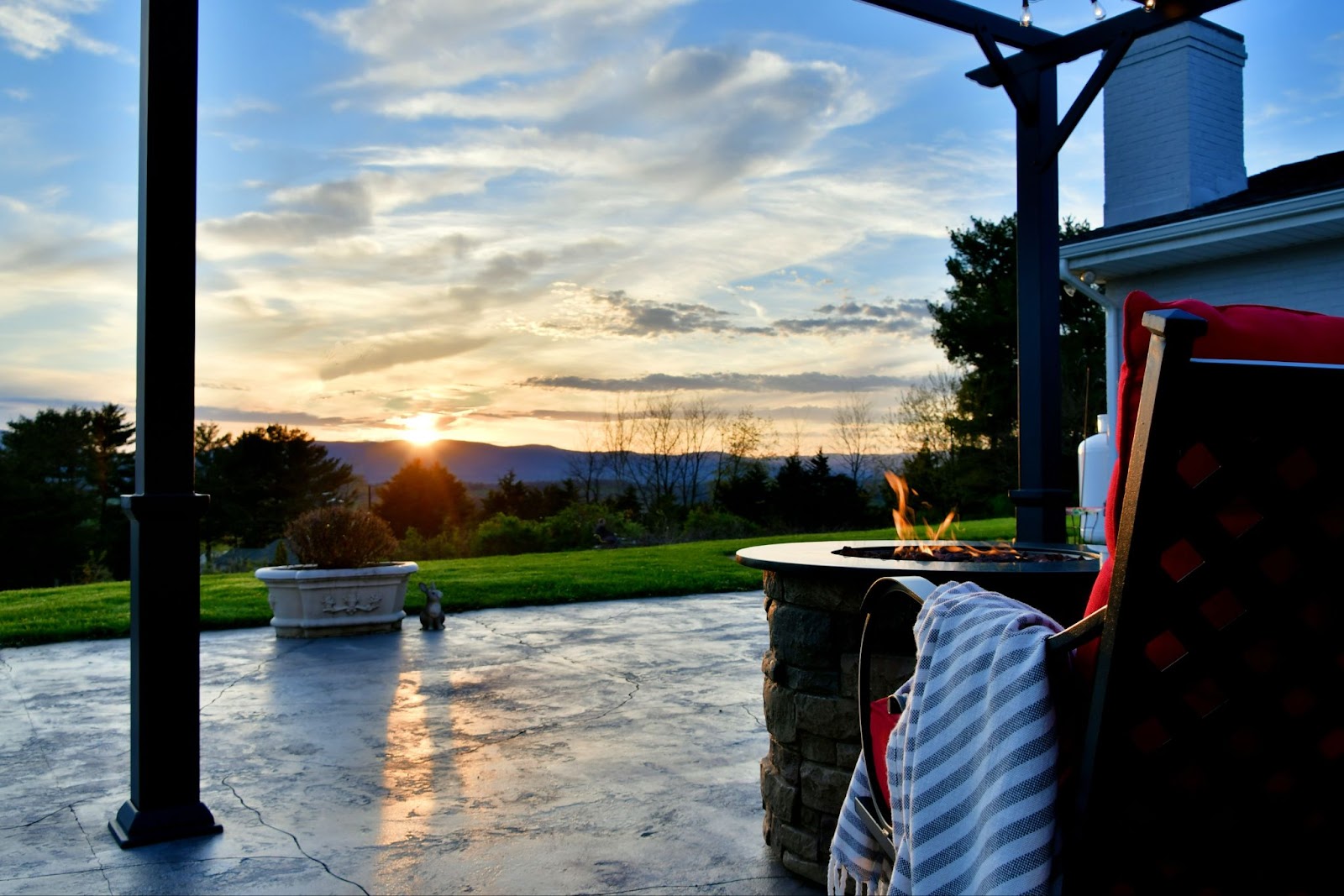 Concrete patio with chairs and a firepit. 