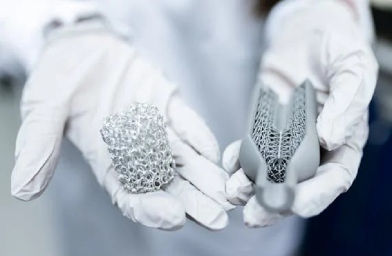 A pair of gloved hands holding two 3D printed medical implants