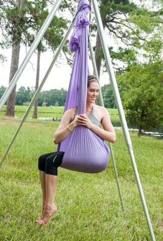 woman sitting on a swing doing aerial yoga to help improve digestion 