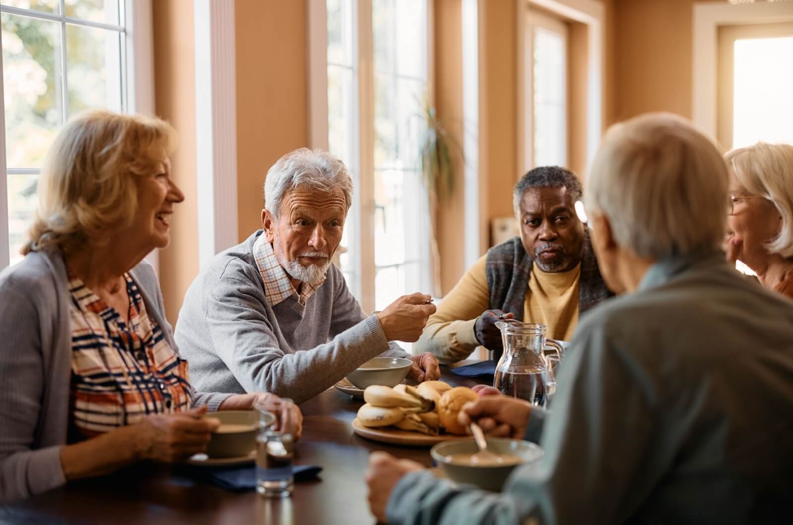 A group of older adults socializing during a meal in senior living.