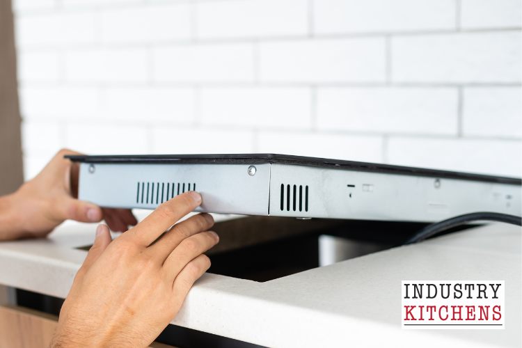 An individual adjusts an induction cooktop, highlighting the importance of proper installation for induction cooking appliances.