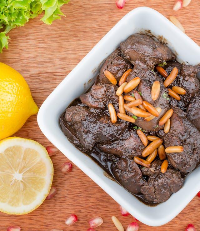 A bowl of food with pine nuts and lemons

Description automatically generated