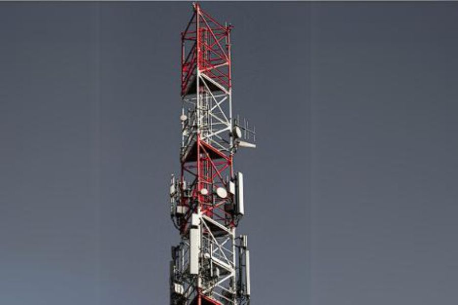 A tall communication tower with red and white structural components and antennas.