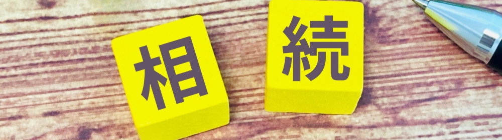 木目の机の上に置かれた黄色いブロック２個に「相」「続」の文字が書かれ、横にペンが置かれたイメージ