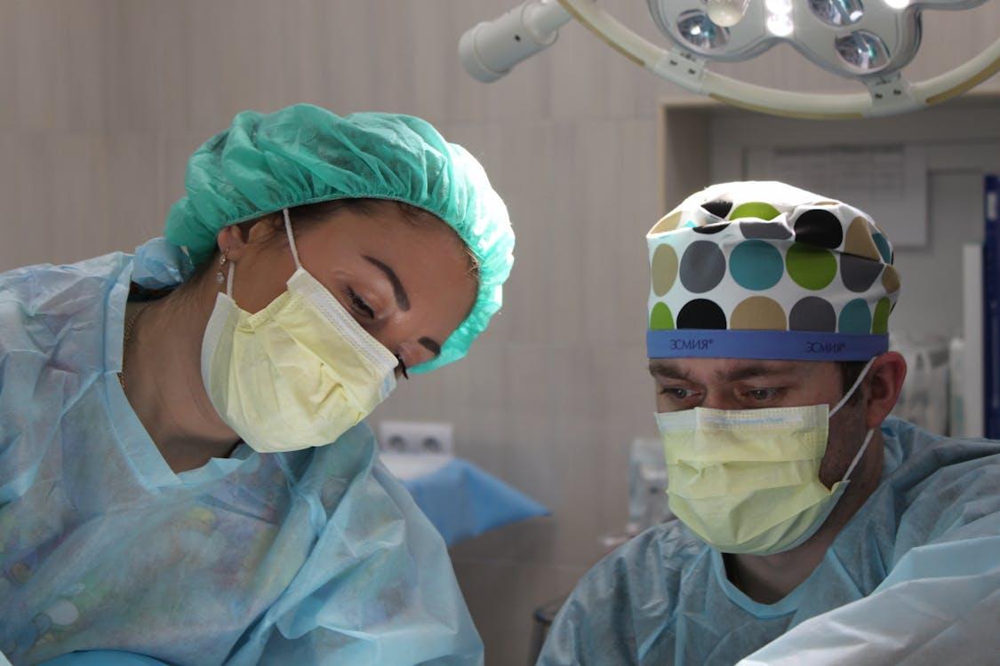 Free Surgeons wearing masks and scrubs conduct an operation in a hospital setting. Stock Photo