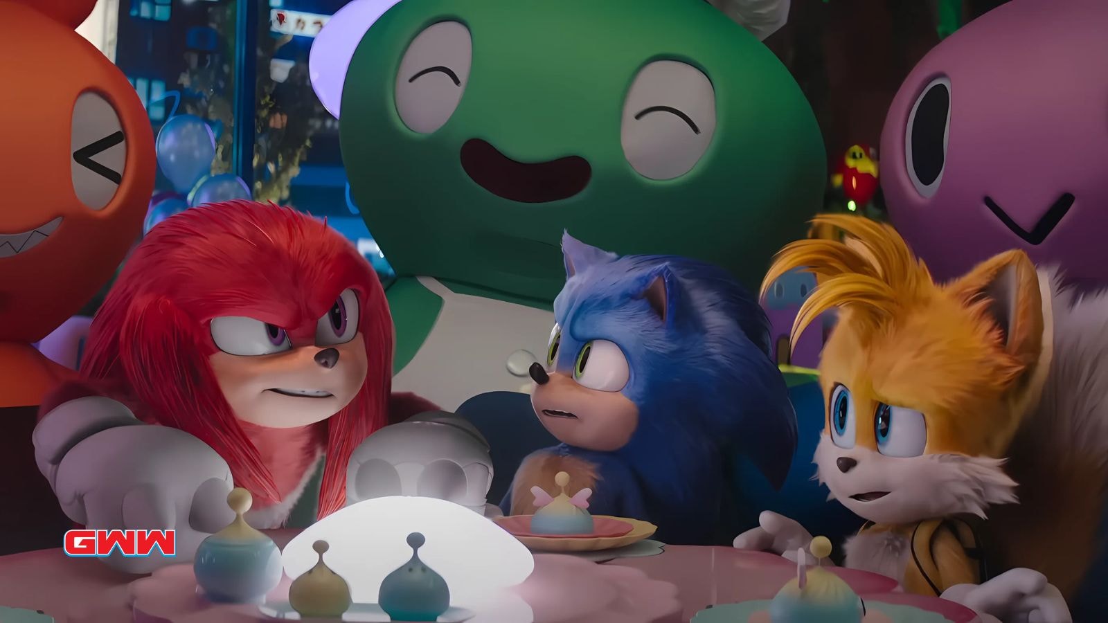 Sonic, Knuckles, and Tails gathered at a table with colorful decorations.