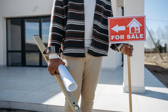 person holding up a red for sale sign